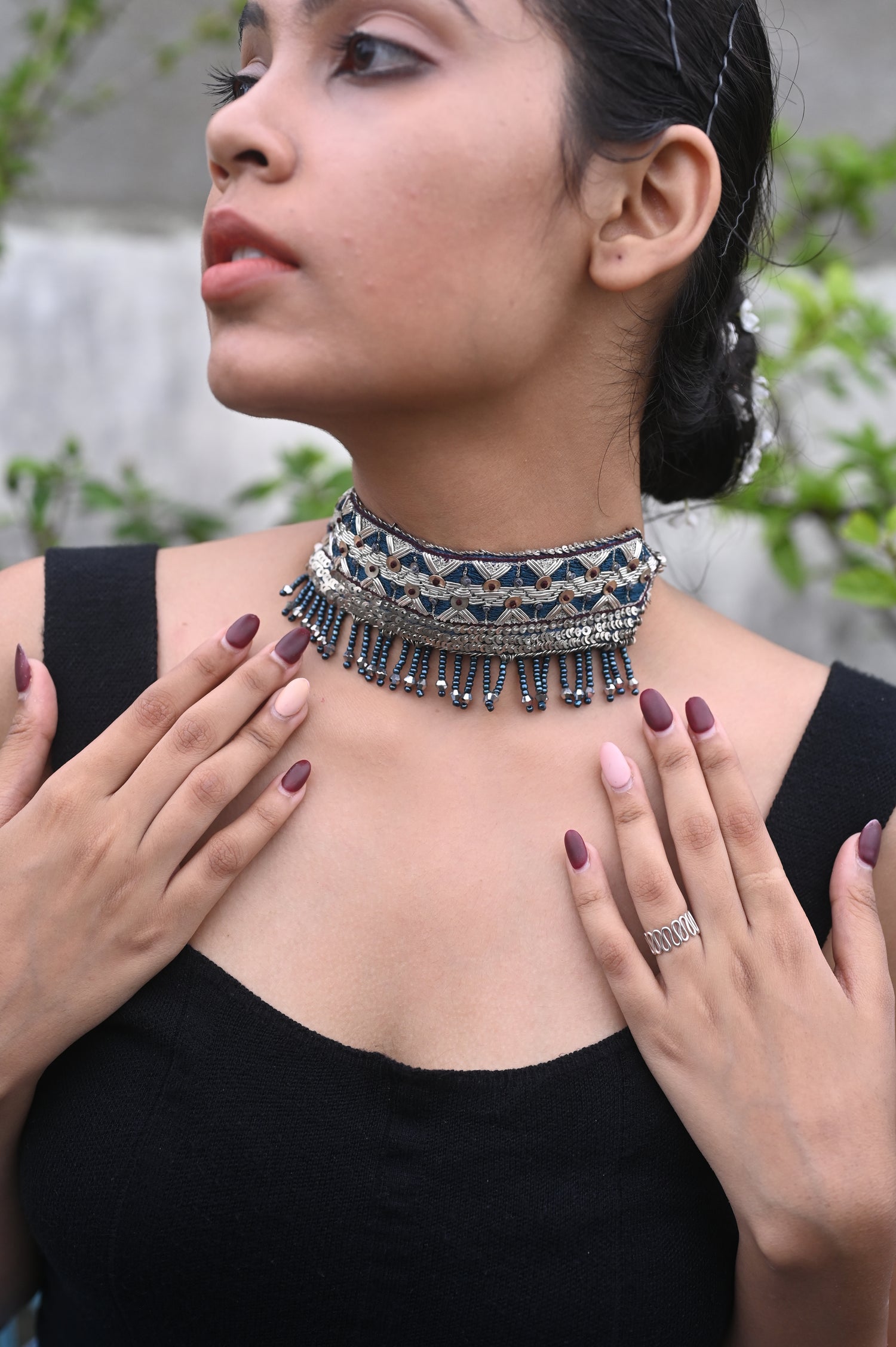 Woman wearing a black top with a decorative neckline, standing outdoors.